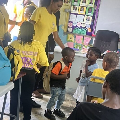 Happy students interacting with each other after receiving their backpack and package from the Love of Hearts Foundation